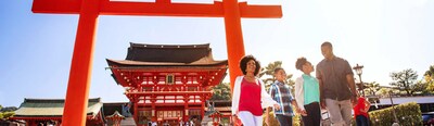 A family of 3 and an Adventure Guide walk in front of the Fushimi Inari Shrine in Kyoto, Japan