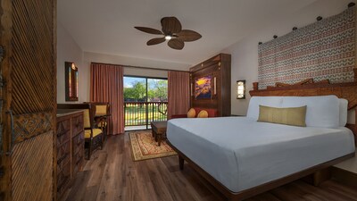 A Deluxe Studio with a king bed, couch, dining table with chairs and a balcony at Disney's Animal Kingdom Villas Kidani Village