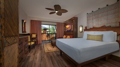 A Deluxe Studio with a king bed, couch, dining table with chairs and a balcony at Disney's Animal Kingdom Villas Kidani Village