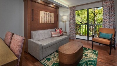 A common area in a 1 Bedroom Villa Resort View room at Copper Creek Villas & Cabins at Disney's Wilderness Lodge with a dining table, a low table, a sofa, a chair and a balcony with Resort views