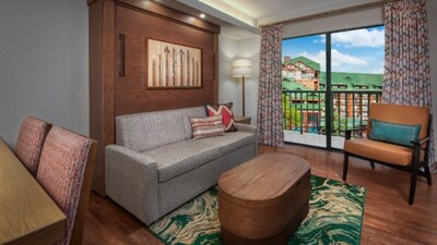A common area in a 2 Bedroom Lock Off Villa Resort View room at Copper Creek Villas & Cabins at Disney's Wilderness Lodge with a dining table, a low table, a sofa, a chair and a balcony with Resort views