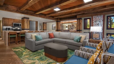 A common area in a 3 Bedroom Grand Villa at Copper Creek Villas & Cabins at Disney's Wilderness Lodge with a kitchen, a counter, 5 stools, a sofa, a coffee table, a lamp table, 2 armchairs and 4 windows with Resort views