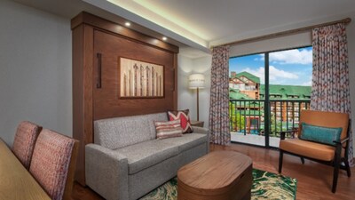 A common area in a 2 Bedroom Lock Off Villa with Shower Resort View room at Copper Creek Villas & Cabins at Disney's Wilderness Lodge with a dining table, a low table, a sofa, a chair and a balcony with Resort views