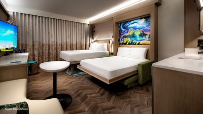 A hotel villa bedroom with a couch, table, TV, dresser, couch table, 2 beds and 'Moana' themed artwork