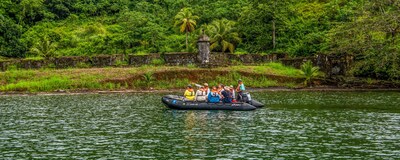 A small boat filled with people passing by lush landscapes in Central America