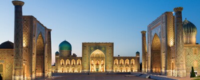 Three madrasahs lit up at night line the sides of an empty Registan Square in Uzbekistan 