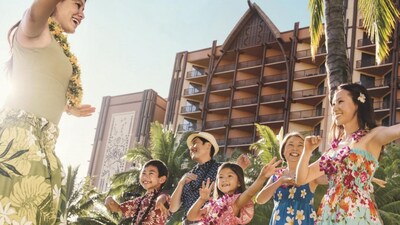 A cast member and a family dancing with the towers of Aulani resort in the background