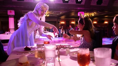 Two children at a table talking to Elsa and enjoying a meal