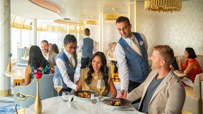 2 waiters delivering plates to a table with 2 Guests in an elegant restaurant setting