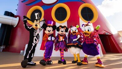 Goofy, Mickey Mouse, Minnie Mouse, Daisy Duck and Donald Duck in Halloween costumes posing for a photo on the top deck of a Disney Cruise Line ship