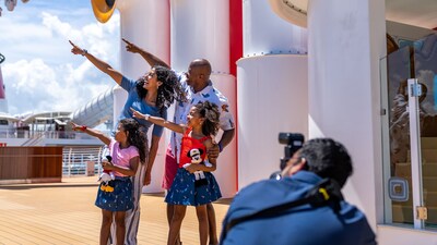 A family in a pointing pose for a photographer on board the Disney Treasure