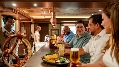 A bartender standing behind a bar while Guests eat, drink and enjoy each other’s company