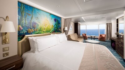 A stateroom featuring The Little Mermaid artwork over the bed and large windows facing the sea