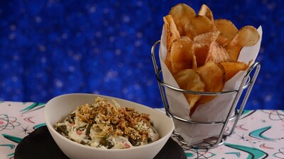 A bowl of spinach and artichoke dip served with a basket of chips