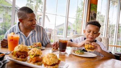 An adult and child eating chicken biscuits together at a table at Chef Art Smith's Homecomin'