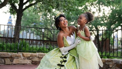 Tiana embracing a young girl wearing a matching Disney Princess gown