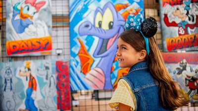 A child looking over her shoulder while standing in front of artwork featuring Daisy, Goofy, Figment and Mickey Mouse 