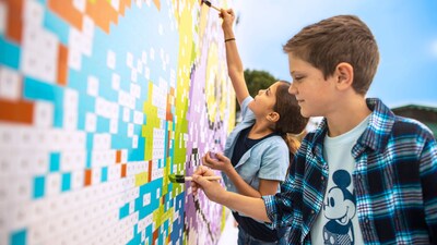 Two children painting a large image of Figment