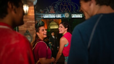 Four smiling young adults approaching the Lightning Lane entrance at the Haunted Mansion