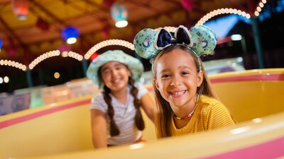Two young girls smiling while sitting in a teacup at the Mad Tea Party attraction