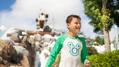 A boy wearing a Mickey Mouse swim shirt while standing in front of the Summit Plummet waterslide at Disney's Blizzard Beach water park