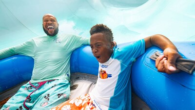 A father and son yelling in excitement as they hold onto the handles of an oversized inner tube on Teamboat Springs at Disney's Blizzard Beach water park