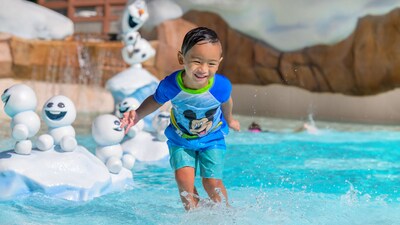 A young boy plays at Tike's Peak near statues of Olaf and Snowgies at Disney's Blizzard Beach water park