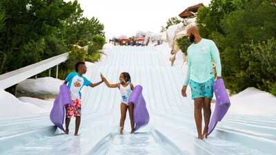 A father smiles as his children high 5 each other at the Toboggan Racers at Disney’s Blizzard Beach water park