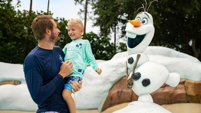 A father holds his young son at the Olaf statue at Tike’s Peak in Disney’s Blizzard Beach water park