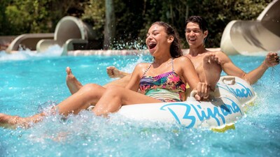 A smiling couple riding an inner tube through a splash of water at Disney’s Blizzard Beach water park