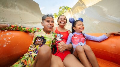 A mother and her 2 kids, all wearing Disney swimwear, gliding down a waterslide at the Miss Adventure Falls attraction at Disney's Blizzard Beach water park