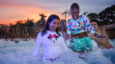 Four Guests joyfully splashing through the foamy waters of Typhoon Lagoon Surf Pool during Disney H2O Glow After Hours