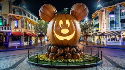 A giant replica jack o lantern with Mickey Mouse's face and 2 pumpkins for ears in a display at one end of Main Street U S A at Disneyland Park