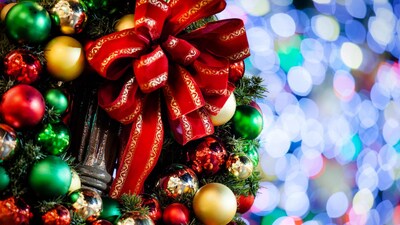 A large bow attached to a lamppost surrounded by a wreath of Christmas ornaments