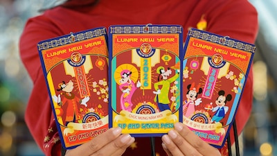 A person holding 3 Lunar New Year Sip and Savor Passes featuring artwork of the Year of the Horse