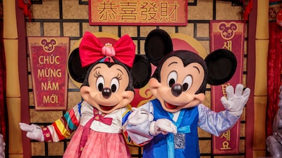 Mickey Mouse and Minnie Mouse in festive costumes, welcoming Guests to a Lunar New Year celebration