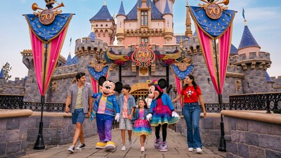Family walking with Mickey and Minnie Mouse in front of the Disneyland castle during the 70th anniversary celebration