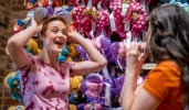 A young woman trying on a Minnie Mouse headband while her friend watches