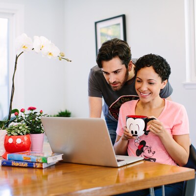 A couple looks at a laptop while sipping coffee