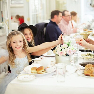 A dining table with 2 women and 2 young girls toasting their drinks together