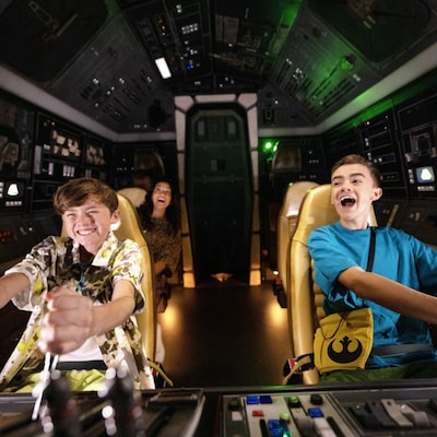 A woman and 2 boys sitting inside Millennium Falcon: Smugglers Run attraction at Disney's Hollywood Studios