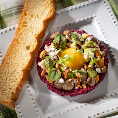 Citrus Braised Beet Tartare topped with pistachio pieces, crumbled cheese, fresh herbs and served with a slice of focaccia bread