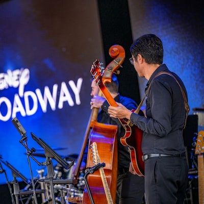 A group of people playing instruments onstage at the Disney On Broadway Concert Series
