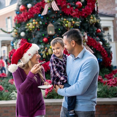 Two parents and their son eating Christmas cookies in front of the Christmas tree on Main Street, USA