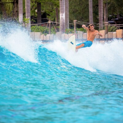 A Guest surfing along a wave in an outdoor wave pool at Disney’s Typhoon Lagoon water park
