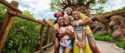 Une famille de quatre personnes qui se serrent dans les bras et sourient devant l’attraction Tree of Life