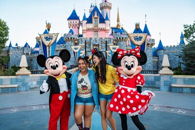 2 Visitantes posan con Mickey Mouse y Minnie Mouse frente al Castillo de la Bella Durmiente en Disneyland Park