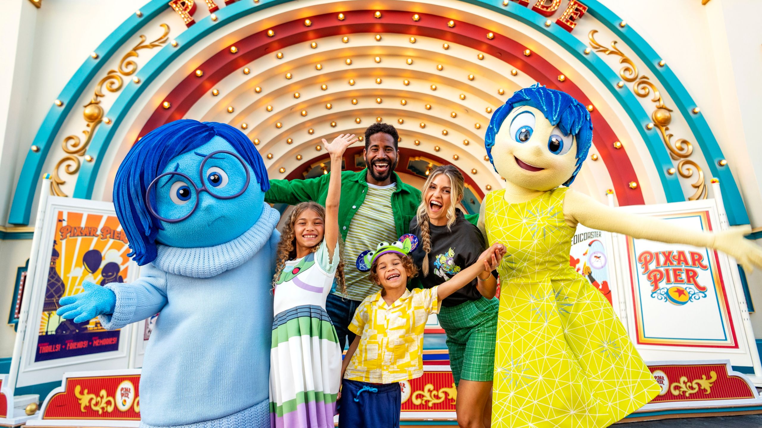 A family takes photos with the characters Joy and Sadness from the Disney and Pixar film Inside Out
