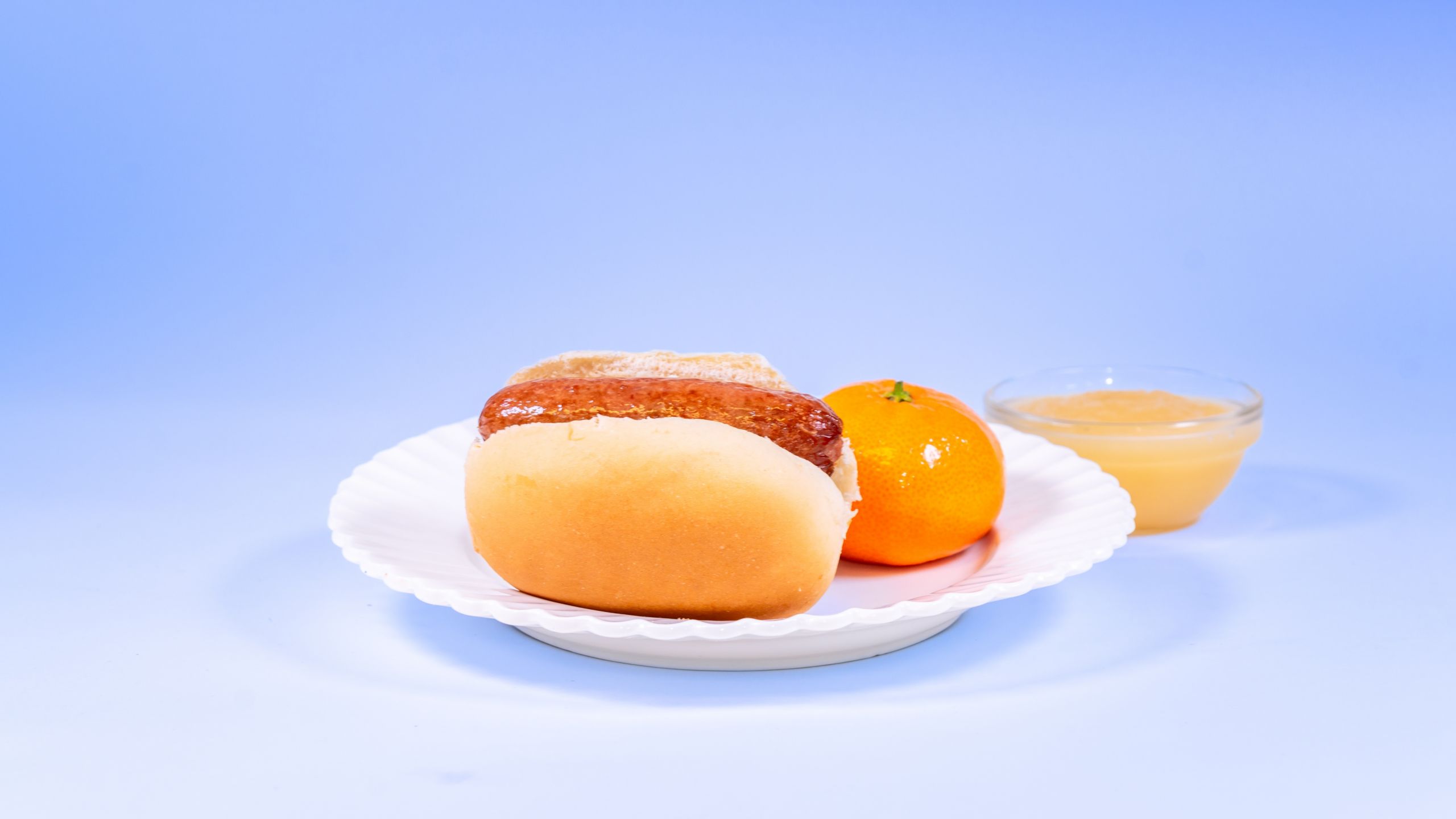 Hot dog on a bun served with a clementine and apple sauce, available during Bluey's Best Day Ever
