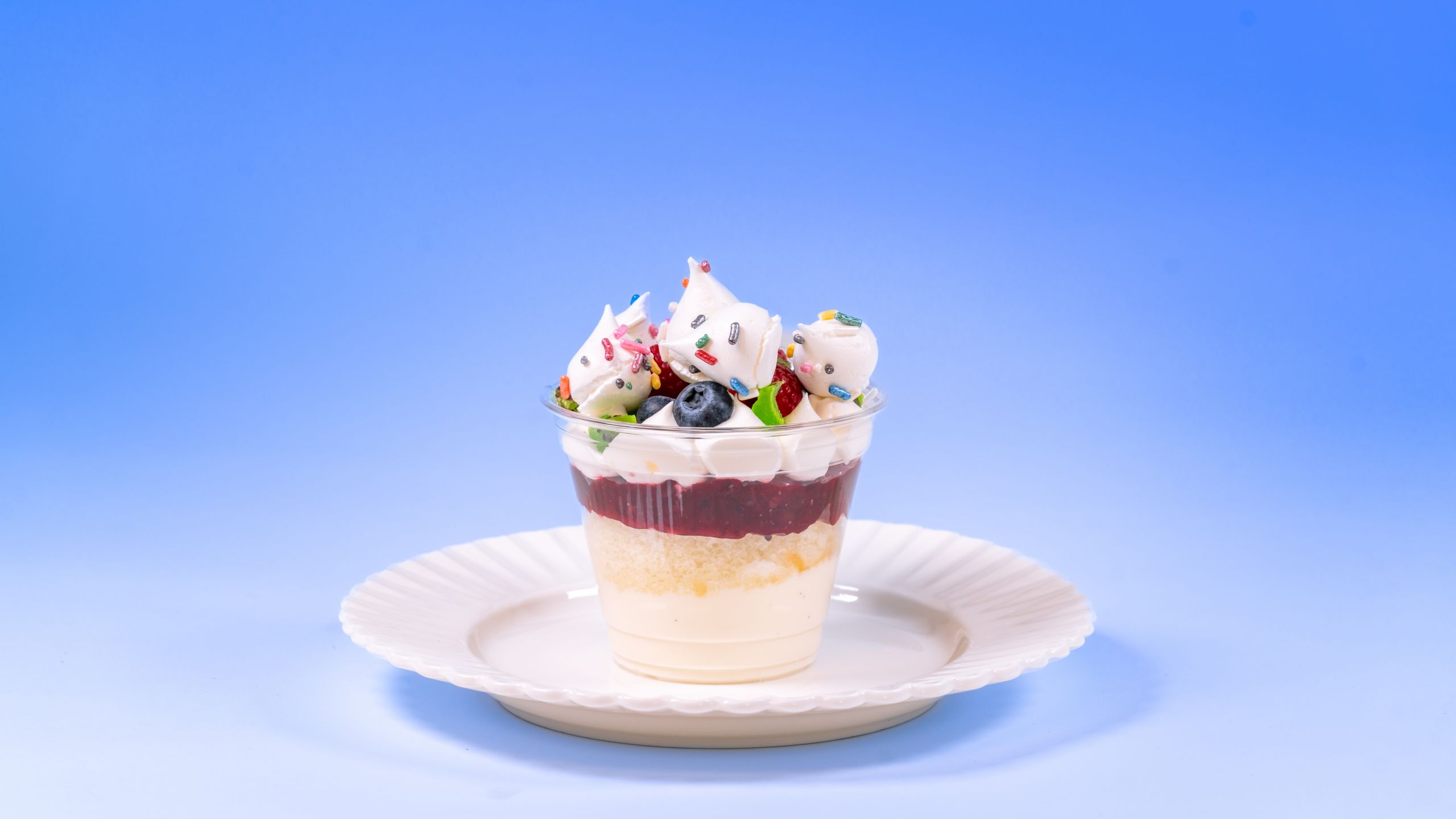 A layered dessert cup with berries, whipped cream and sprinkles, available during Bluey's Best Day Ever
